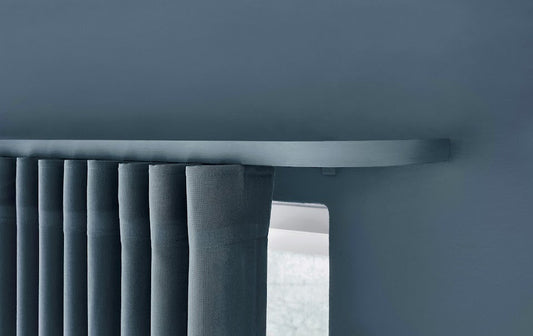 Blå buet gardinskinne med blå velour gardiner på blå væg